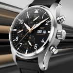 IWC Chronograph im Edelstahlgehäuse mit schwarzem Zifferblatt, goldenen Akzenten und schwarzem Kautschukarmband, inspiriert vom APXGP Rennsportdesign.