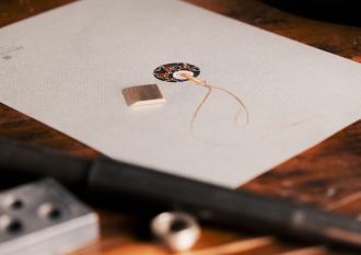 Nahaufnahme eines Schmuckstücks mit Goldfaden auf einem Arbeitstisch im Meisteratelier von Juwelier Mühlbacher in Regensburg.