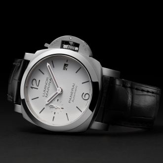 Panerai Luminor Uhr in Stahl mit weissem Zifferblatt und schwarzem Lederarmband seitlich auf grauem Untergrund liegend