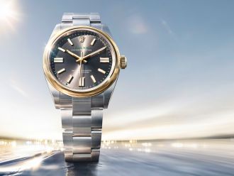 Rolex Oyster Perpetual Armbanduhr in Edelstahl und Gold mit grauem Zifferblatt vor dynamischem, lichtdurchflutetem Hintergrund