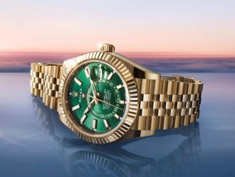 Luxuriöse Rolex Sky-Dweller in Gelbgold mit grünem Zifferblatt vor Sonnenuntergang – exklusive Schweizer Uhr mit automatischem GMT-Uhrwerk und Jubilé-Armband.