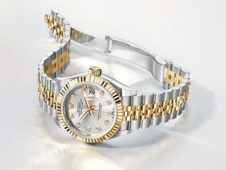 Rolex Lady Datejust in Stahl-Gold mit Perlmuttzifferblatt und geriffelter L&uuml;nette seitlich auf hellgrauem Hintergrund liegend