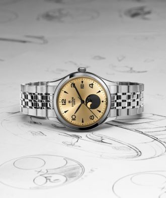 TUDOR 1926 Luna mit champagnerfarbenem Zifferblatt, schwarzer Mondphasenanzeige und Edelstahlarmband, inszeniert auf Zeichnungen des Zifferblatt-Designs.