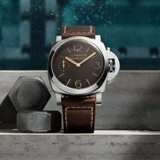 Panerai Luminor mit braunem Zifferblatt und Lederarmband auf industrieller Metalloberfl&auml;che &ndash; ikonische Taucheruhr mit markantem Kronenschutzb&uuml;gel