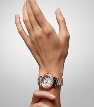 Damenarm mit einer Happy Sport Uhr von Chopard in Rosegold mit Diamantluenette und weissem Zifferblatt mit fuenf beweglichen Diamanten am Handgelenk