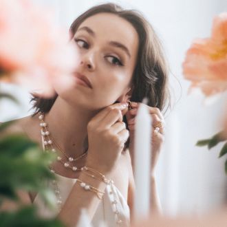 Frau trägt eleganten Perlschmuck von Yana Nesper mit Collier, Armband, Ringen und Ohrringen – zeitlose Eleganz und modernes Design