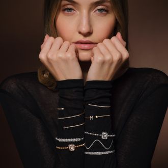 Modell tr&auml;gt mehrere feine Armb&auml;nder und Armreifen aus Gold und Silber mit Diamanten, elegant kombiniert am Handgelenk.
