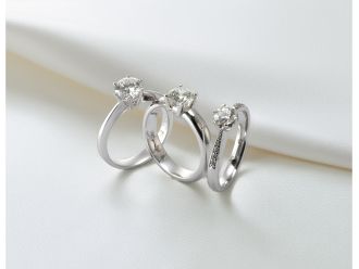 Drei klassische Solitär-Verlobungsringe aus Weißgold mit einzeln gefasstem Diamanten in Krappenfassung auf hellem Stoff