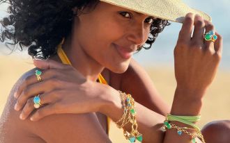 Weibliches Model im Strandlook traegt mehrere Schmuckstuecke von Tamara Comolli