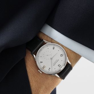 Herrenhandgelenk mit einer Minimatik Uhr von NOMOS Glashuette in Stahl mit weissem Zifferblatt und einem schwarzem Lederarmband