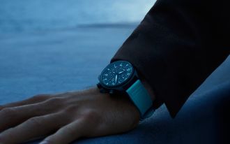 IWC Pilot&rsquo;s Watch George Russell am Handgelenk getragen, mit schwarzem Chronographenzifferblatt und blauem Kautschukarmband in dunkler Atmosph&auml;re