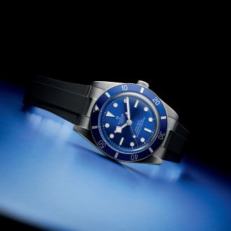 Tudor Black Bay Taucheruhr mit blauem Zifferblatt und L&uuml;nette, Edelstahlgeh&auml;use und schwarzem Kautschukband, modern inszeniert auf blau-schwarzem Hintergrund