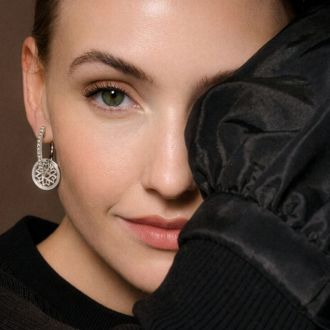 Ohrh&auml;nger aus Wei&szlig;gold mit Diamanten in rundem Design, getragen am Ohr, elegante Detailaufnahme.