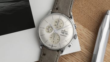 Junghans Meister Chronograph in Stahl mit silbergrauem Zifferblatt und taupefarbenem Lederarmband auf Schreibtisch liegend