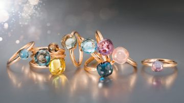 Mehrere Ringe aus der Happy Holi Kollektion con Capolavoro in Rosegold mit verschiedenen Farbedelsteinen auf grauem Hintergrund