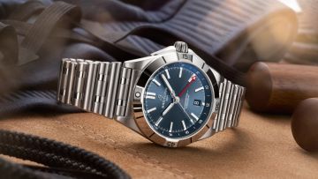 Breitling Chronomat Uhr in Stahl mit blauem Zifferblatt seitlich auf Stoffuntergrund liegend