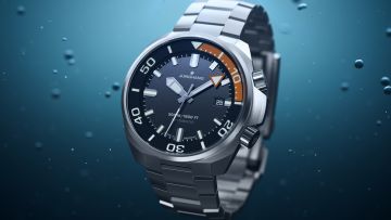 Detailaufnahme der Junghans Aquaris Diver mit Leuchtindizes und orange markiertem Drehring vor Unterwasser-Hintergrund.