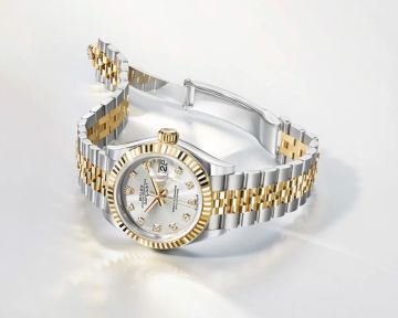 Rolex Lady Datejust in Stahl-Gold mit Perlmuttzifferblatt und geriffelter Lünette seitlich auf hellgrauem Hintergrund liegend