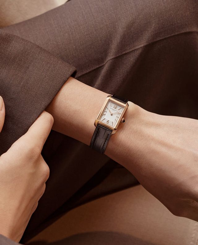 Weibliches Model mit Hampton Uhr in Gelbgold mit weissem Zifferblatt und Lederarmband am Handgelenk