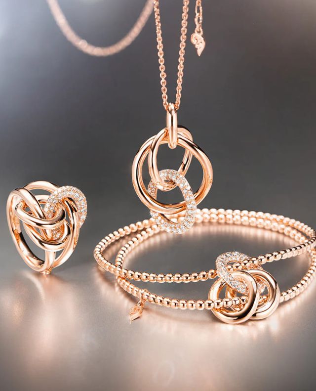 Capolavoro Cielo Ring, Armband und Halskette mit Anhaenger in Rosegold mit Diamanten auf grauem Hintergrund