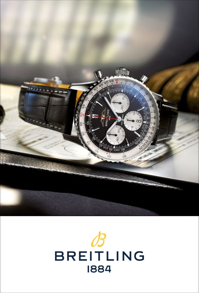 Breitling Navitimer Chronograph in Stahl mit schwarz-silbernem Pandazifferblatt und schwarzem Lederarmband seitlich auf Flugunterlagen liegend