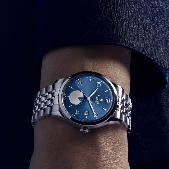 Am Handgelenk getragene TUDOR 1926 Luna mit blauem Zifferblatt, Edelstahlarmband und silberner Mondphasenanzeige im Lichtspiel.