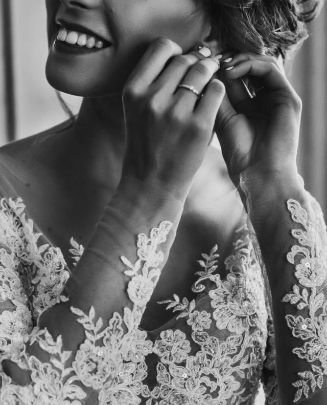 Braut macht sich fuer ihren grossen Tag fertig und zieht ihre Ohrringe an