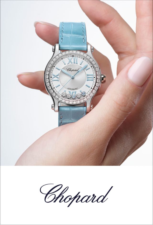 Damenhand haelt eine Chopard Happy Sport Uhr in Stahl mit Diamantluenette und hellblauem Lederarmband hoch