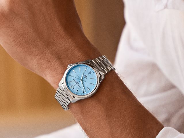 Mann im wei&szlig;en Hemd tr&auml;gt eine Clifton von Baume & Mercier mit Edelstahlarmband und eisblauem Zifferblatt.