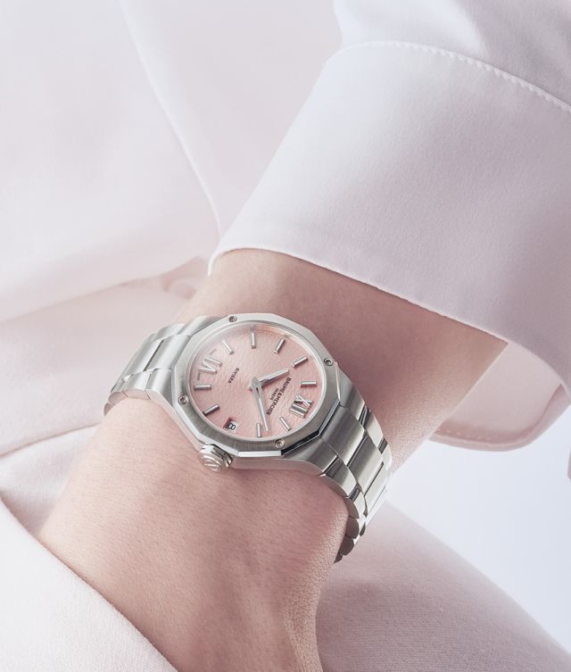 Baume & Mercier Riviera Damenuhr mit rosefarbenem Zifferblatt und Edelstahlarmband am Handgelenk.