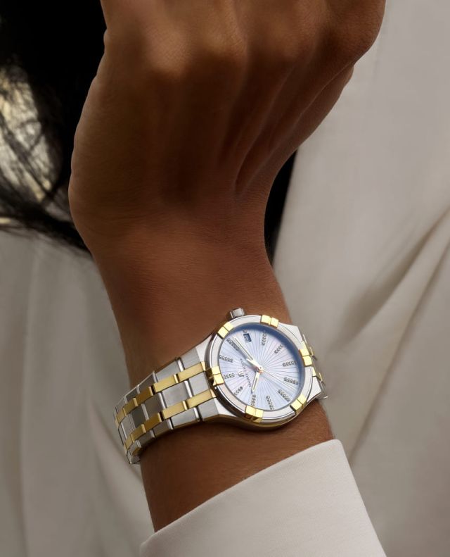 Maurice Lacroix Aikon Uhr mit Gehaeuse und Armband in Stahl und Gelbgold mit grausilbernem Zifferblatt an weiblichem Handgelenk