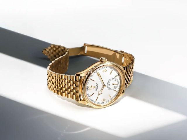 Rolex 1908 in Gelbgold mit Jubile-Armband und weißem Zifferblatt, stilvoll im Querformat fotografiert mit elegantem Lichteinfall für edle Produktpräsentation.