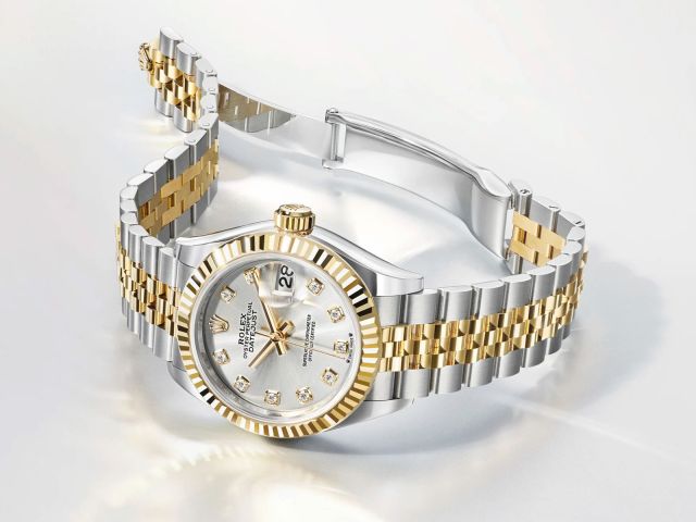 Rolex Lady Datejust in Stahl-Gold mit Perlmuttzifferblatt und geriffelter L&uuml;nette seitlich auf hellgrauem Hintergrund liegend