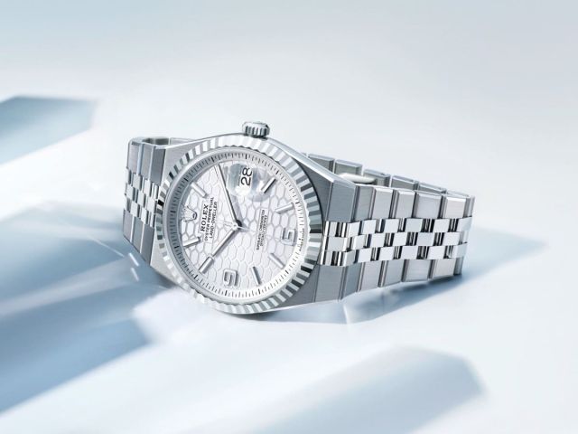 Rolex Land-Dweller Armbanduhr aus Edelstahl mit silbernem Jubilé-Armband und hellem strukturiertem Zifferblatt auf hellem Hintergrund inszeniert.