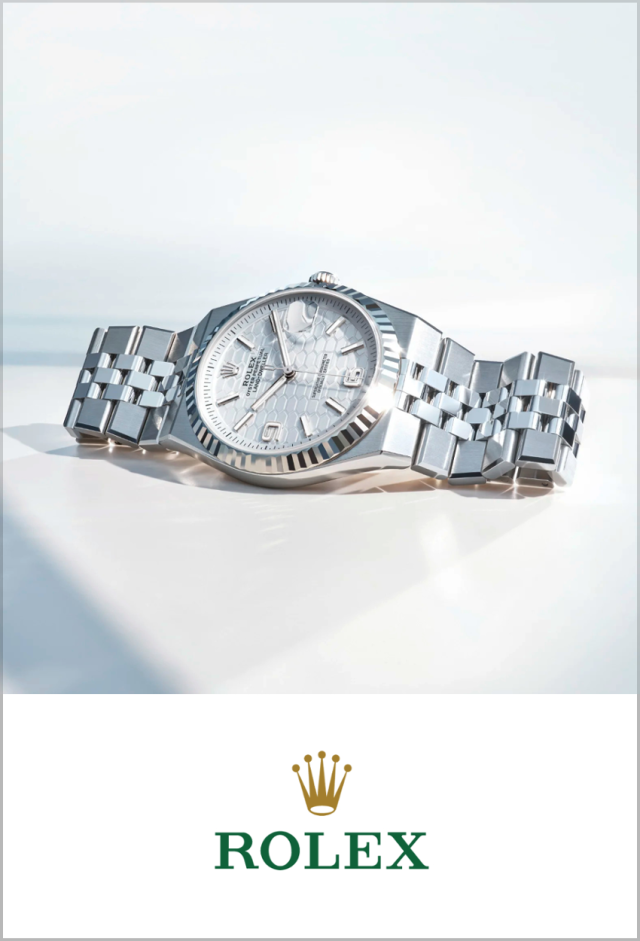 Detailaufnahme der Rolex Land-Dweller Armbanduhr aus Edelstahl mit Jubilee-Armband und strukturiertem silberfarbenem Zifferblatt, darunter Rolex Markenlogo auf wei&szlig;em Hintergrund.