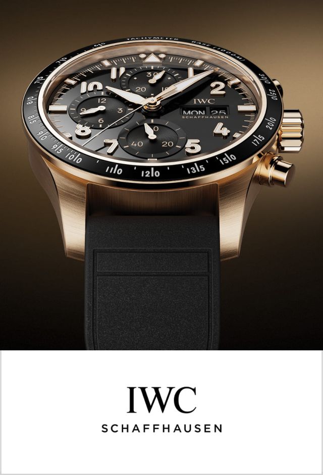 IWC Pilots Watch in Gold mit schwarzer Luenette, Zifferblatt und Kautschukband vor goldbraun-schwarzem Hintergrund