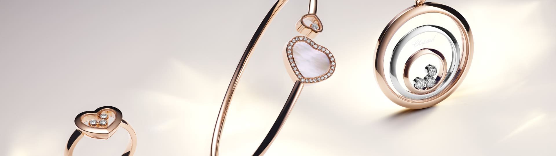Chopard Happy Diamonds Ring in Rosegold mit 3 beweglichen Diamanten, Happy Hearts Armreif in Rosegold mit Diamanten und weissem Perlmutt, Happy Spirit Anhaenger in Rose- und Weissgold