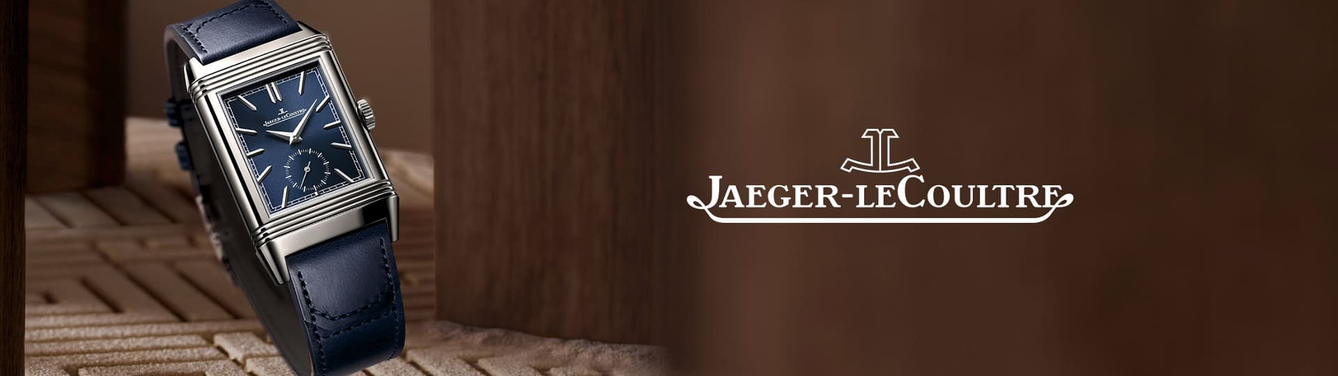 Seitliche Ansicht der Jaeger-LeCoultre Reverso Uhr mit blauem Zifferblatt und Lederarmband, stilvoll inszeniert zwischen Holzelementen mit prominentem Markenlogo rechts.