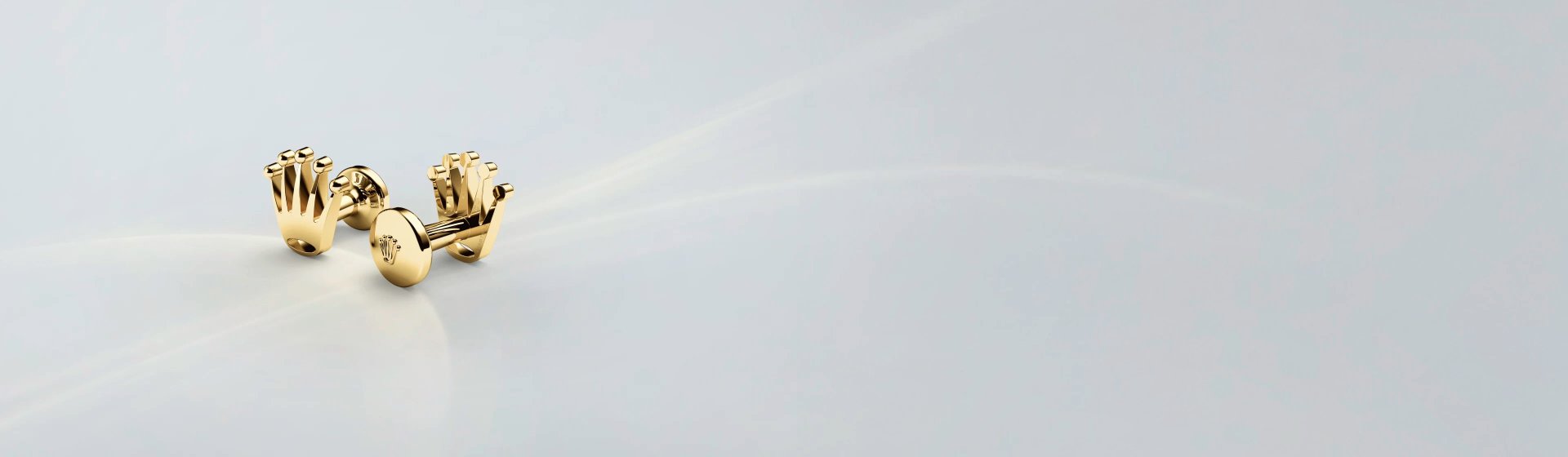 Rolex Manschettenknöpfe aus 18 Karat Gelbgold mit geprägter Rolex Krone, stilvoll inszeniert auf hellem Hintergrund, exklusives Schmuck-Accessoire