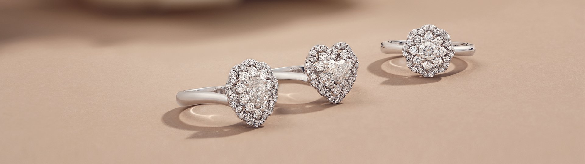 Crivelli Verlobungsringe aus Weißgold mit Herz- und Ovaldesign auf sandbraunem Untergrund
