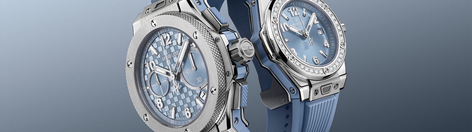 Zwei Hublot Uhren mit blauem Zifferblatt und blauem Kautschukarmband, Big Bang Chronograph und Classic Fusion mit Diamantl&uuml;nette, Edelstahlgeh&auml;use vor k&uuml;hlem blauem Hintergrund