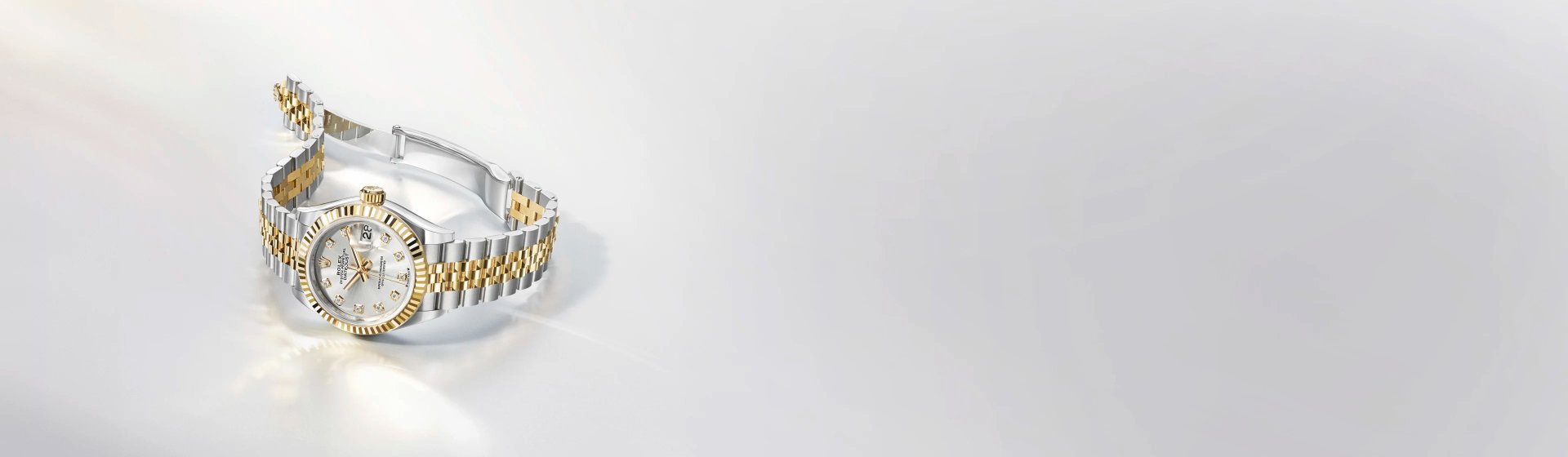 Rolex Lady Datejust in Stahl-Gold mit Perlmuttzifferblatt und geriffelter L&uuml;nette seitlich auf hellgrauem Hintergrund liegend