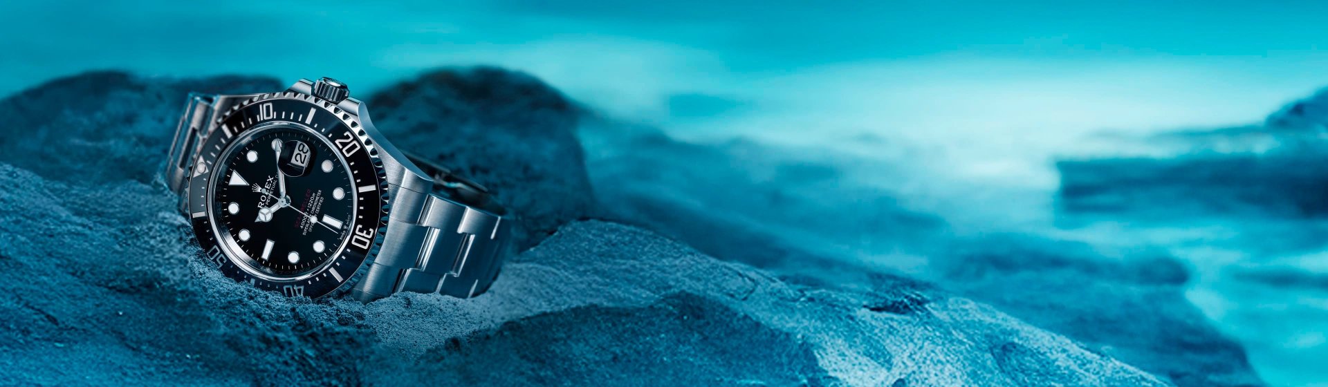 Rolex Sea-Dweller in Edelstahl mit schwarzem Zifferblatt und schwarzer Luenette am Meeresuntergrund liegend
