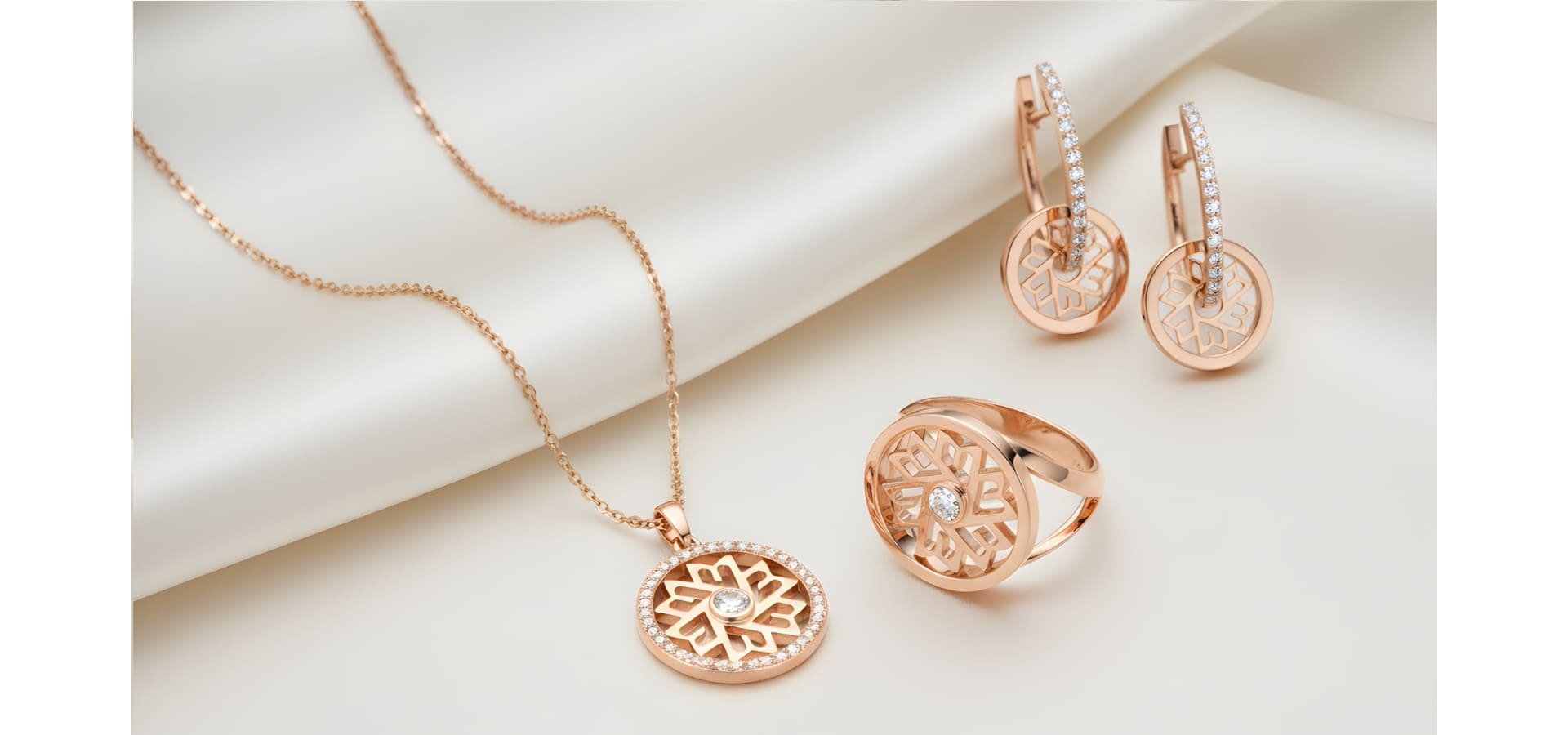 Schmuckstücke der Danuvina Mill River Collection von Mühlbacher aus Rosegold auf cremefarbenem Stoff arrangiert.