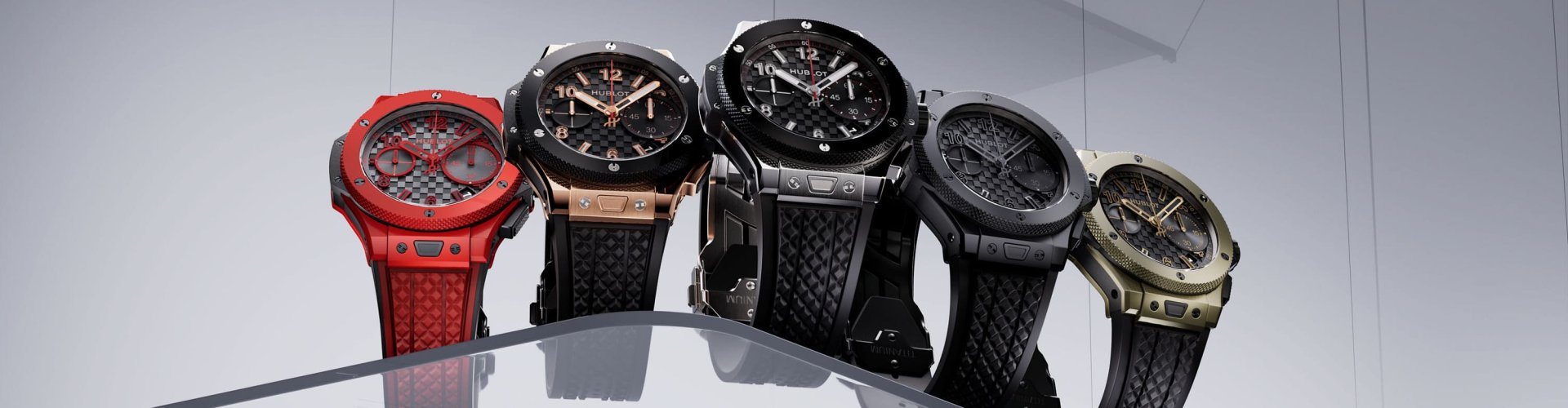Fuenf Hublot Big Bang 20th Anniversary Uhren nebeneinander vor grauem Hintergrund