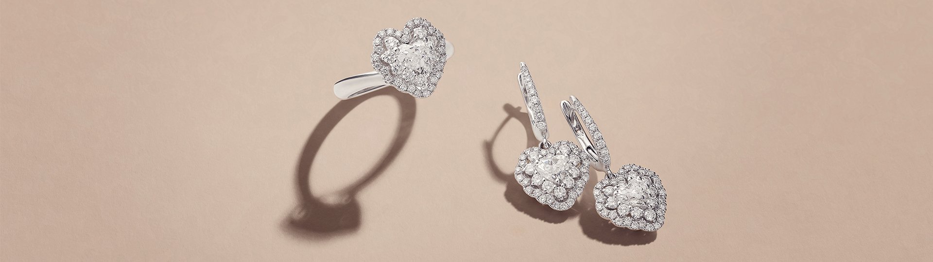 Schmuckstücke aus der Crivelli I Will I Do Kollektion mit Diamantring und Diamantohrringen aus Weißgold auf sandbraunem Untergrund