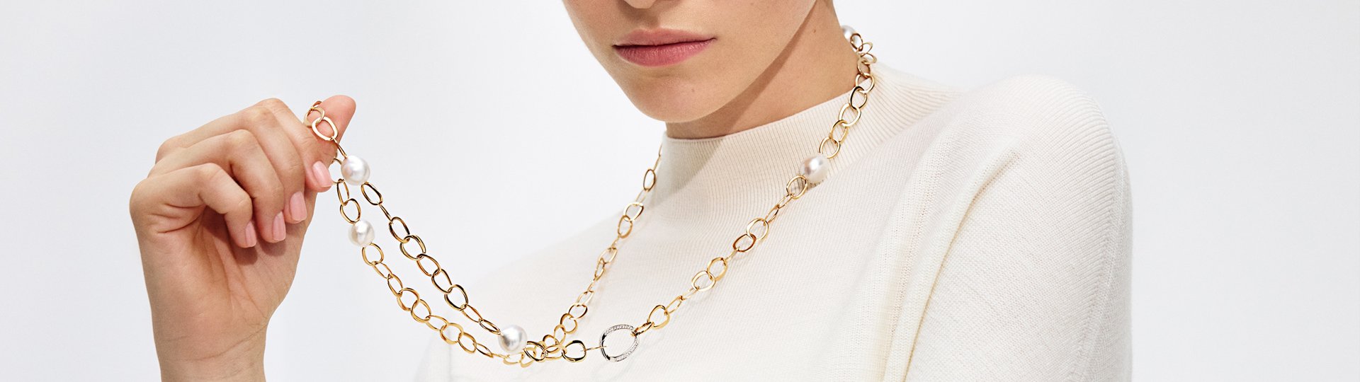Model trägt eine Gellner Halskette aus Gelbgold mit weißen Perlen.
