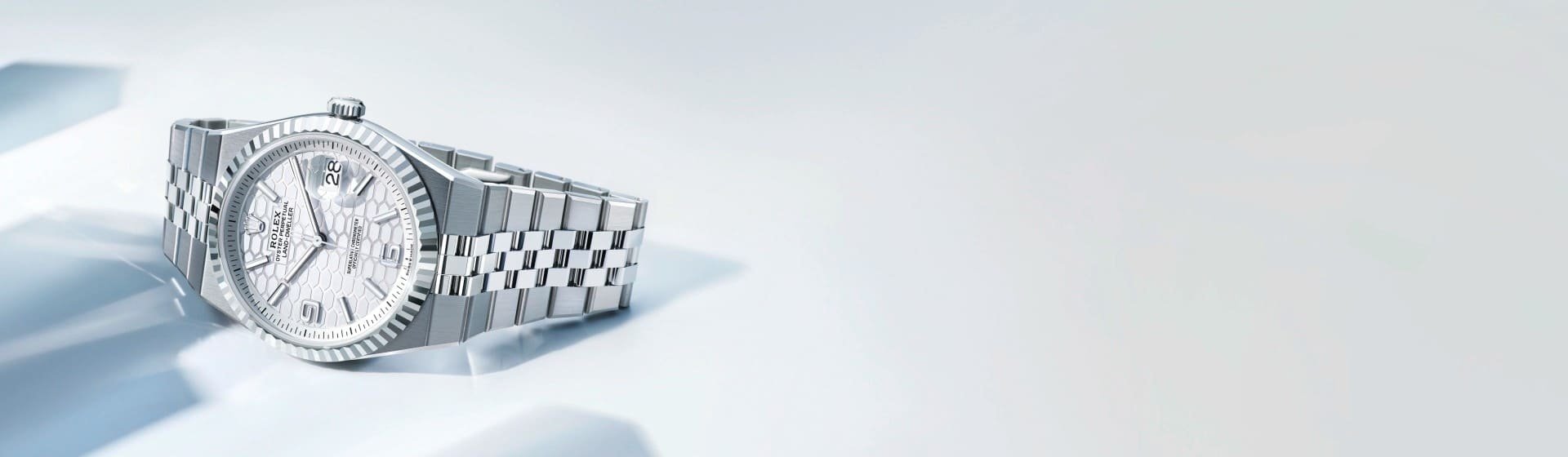 Rolex Land-Dweller Armbanduhr aus Edelstahl mit silbernem Jubilé-Armband und hellem strukturiertem Zifferblatt auf hellem Hintergrund inszeniert.