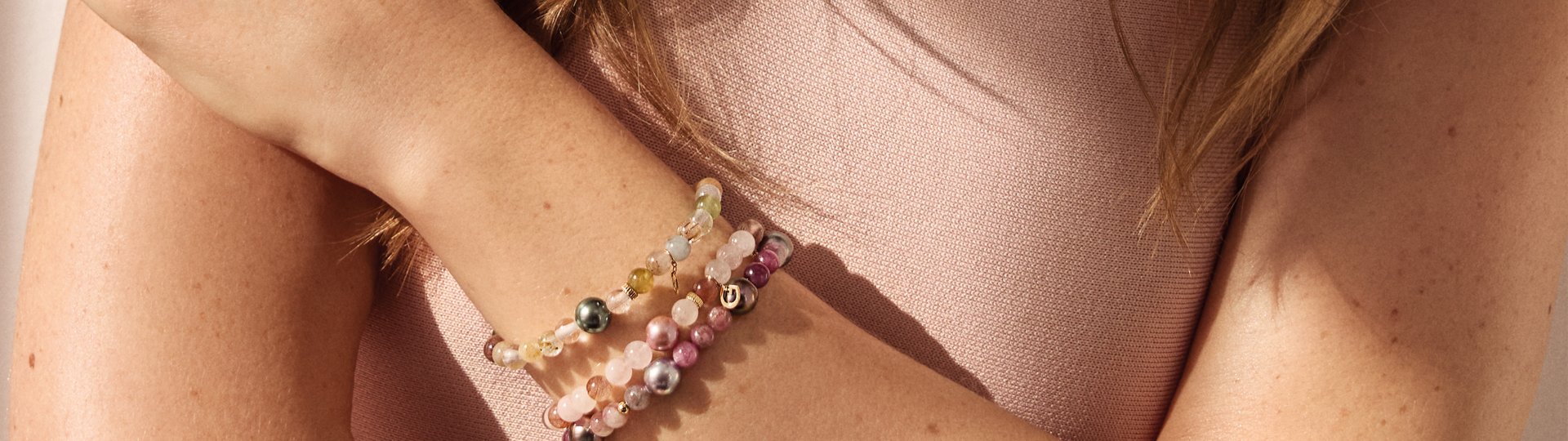 Detailaufnahme mehrerer Gellner Armb&auml;nder mit Perlen und Edelsteinen am Handgelenk eines Models.