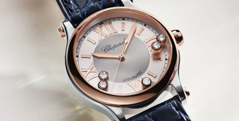 Chopard Happy Sport Damenuhr mit Gehaeuse in Stahl, Krone und Luenette in Rosegold, silbernem Zifferblatt mit roemischen Ziffern und 5 beweglichen Diamanten vor beigefarbenem Hintergrund Chopard Happy Sport Damenuhr mit Gehaeuse in Stahl, Krone und Luenette in Rosegold, silbernem Zifferblatt mit roemischen Ziffern und 5 beweglichen Diamanten vor beigefarbenem Hintergrund